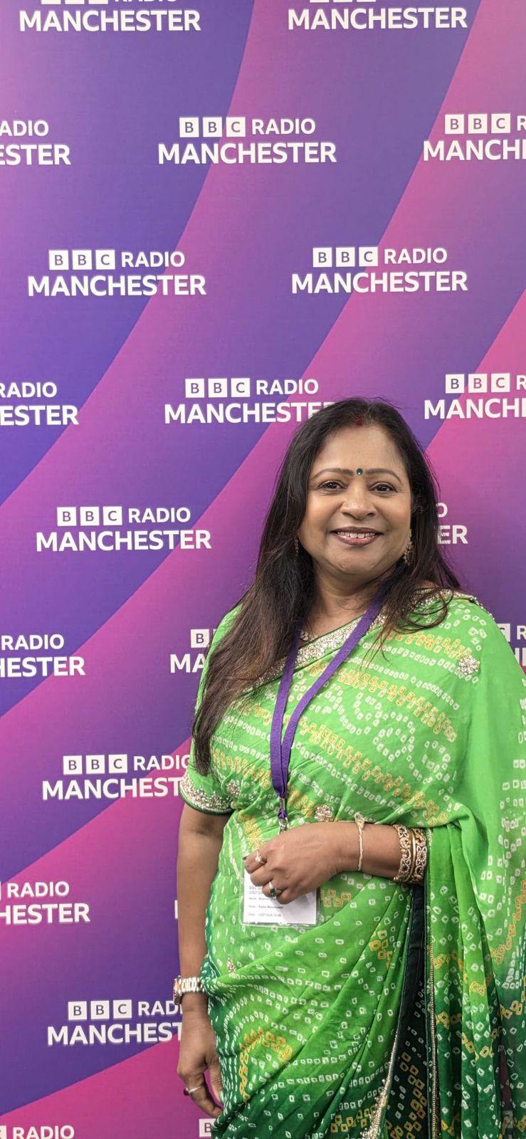 Bhavana Ghosh in a green saree in front of the BBC Radio Manchester backdrop