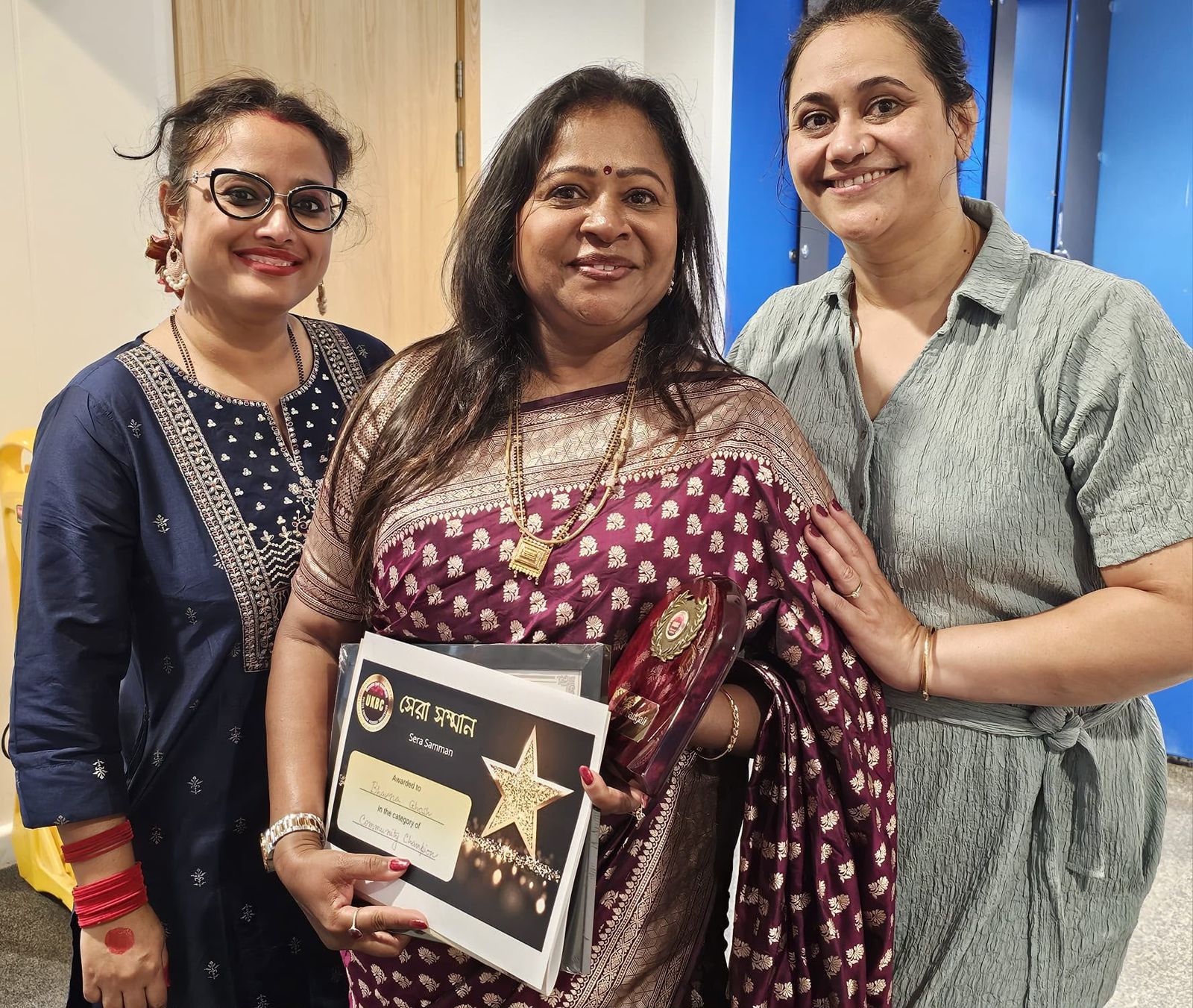Bhavana Ghosh with friends holding the UKBC Sera Samman award certificate and trophy